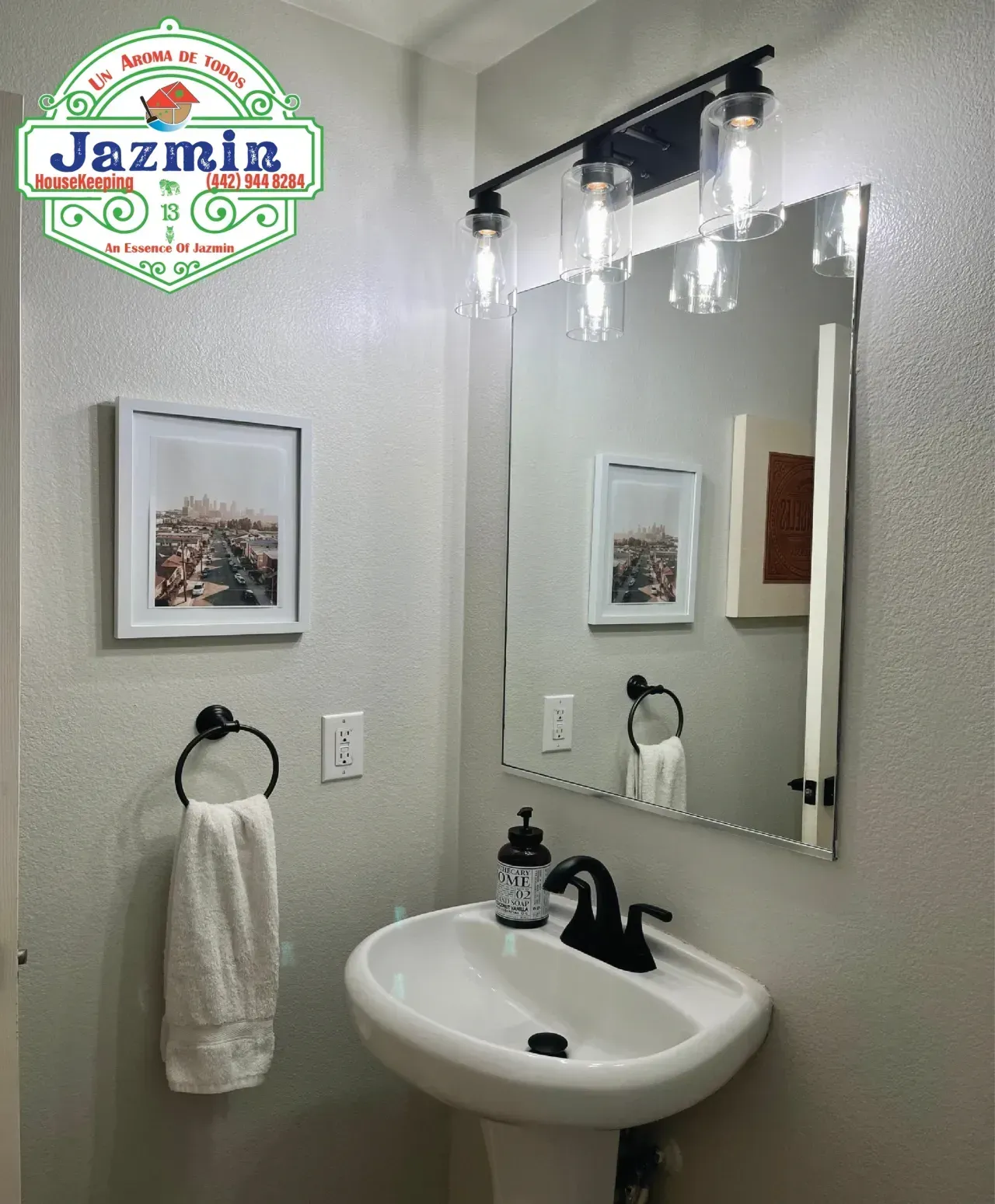 Small bathroom vanity with round sink, mirror, black faucet, and towel ring on gray walls
