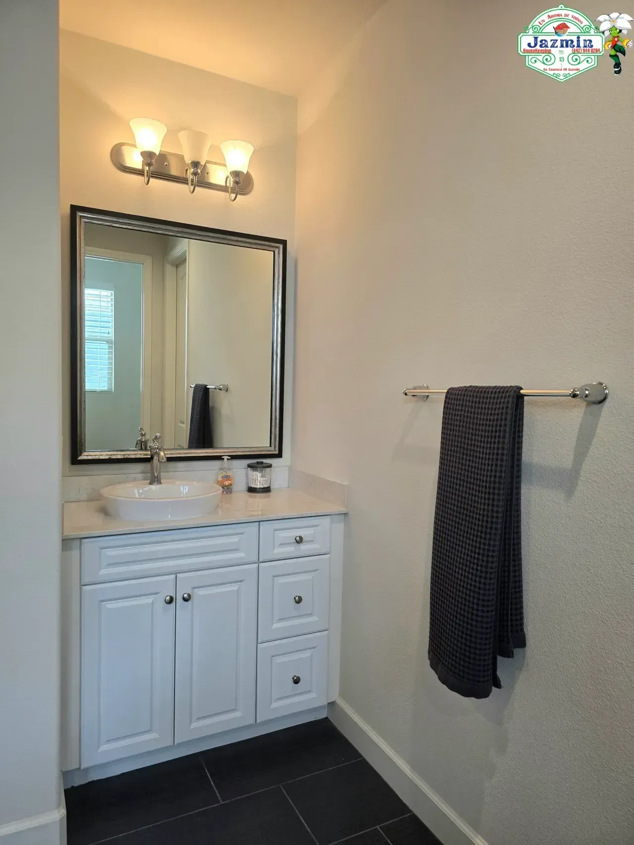 Bathroom vanity with mirror, wall light, towel bar, and dark tile floor
