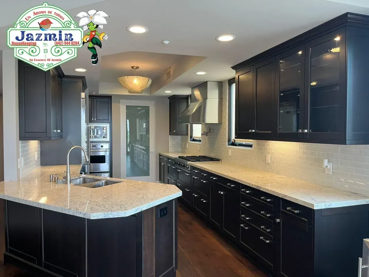Modern kitchen with dark cabinets, granite island, stainless appliances, and tile backsplash.