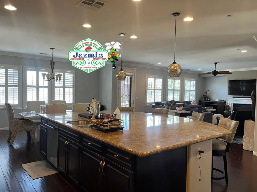 Modern kitchen with a large island, pendant lights, bar stools, and open dining and living areas