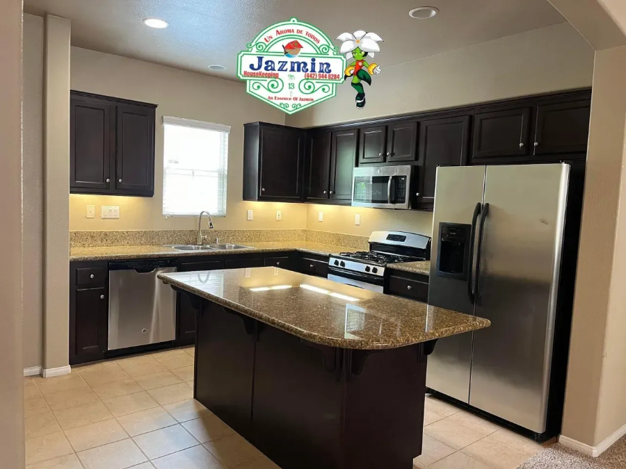 Modern kitchen with dark cabinets, granite island, stainless steel appliances, and tiled floor