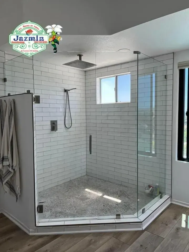 Glass-enclosed tiled shower with rainfall showerhead, handheld sprayer, and bench seat