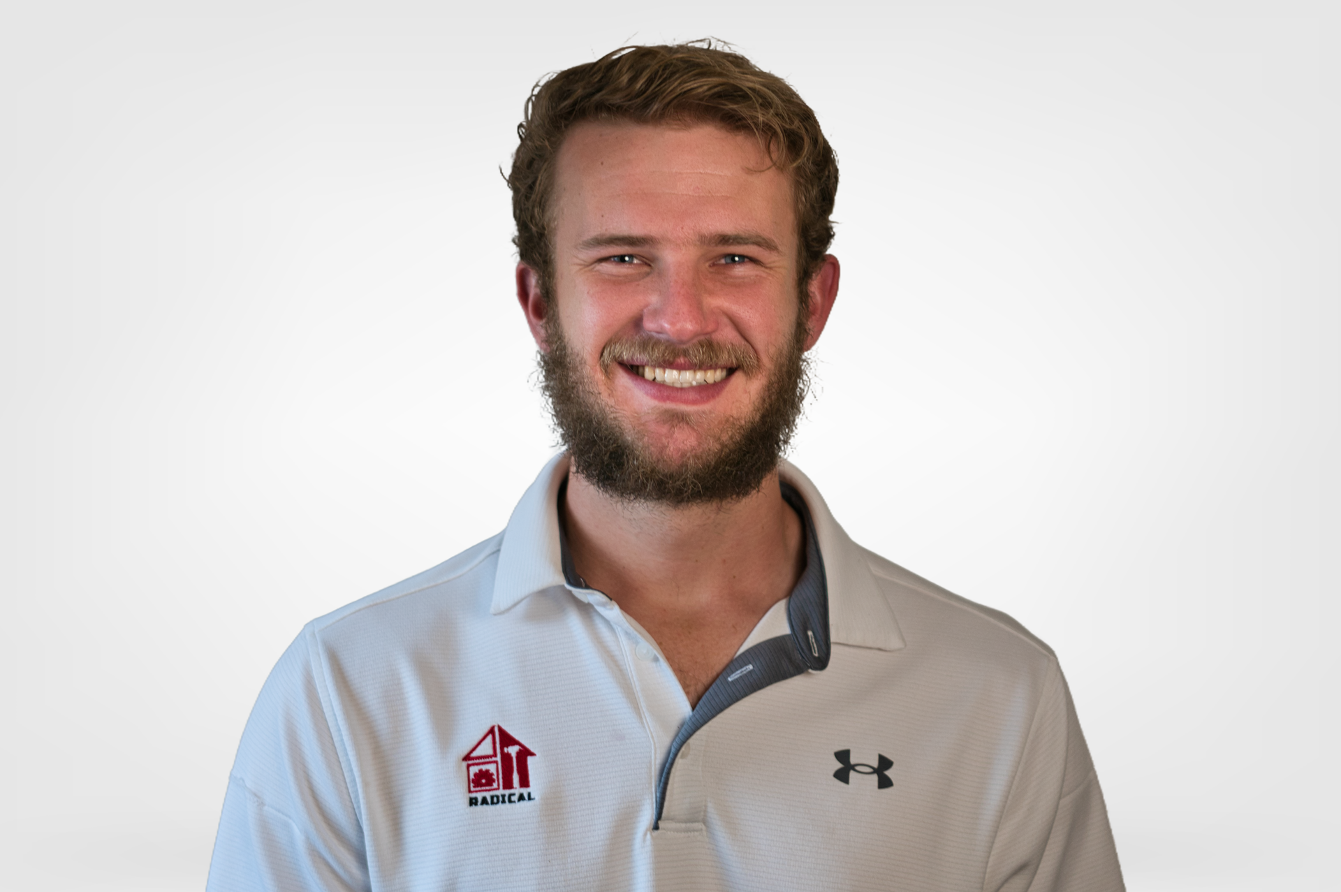 Smiling man in a light gray collared shirt with logos on a white background