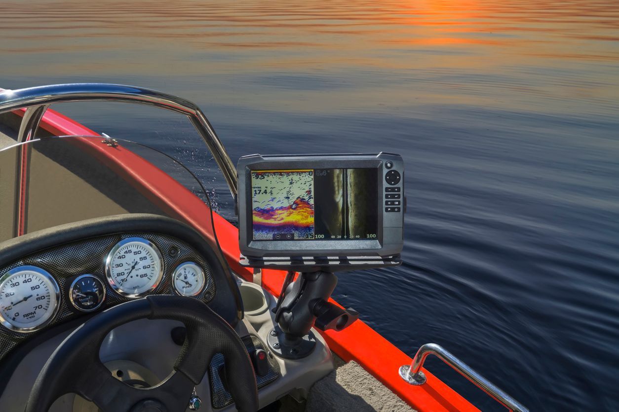 Boat cockpit with gauges and GPS display on calm water at sunset