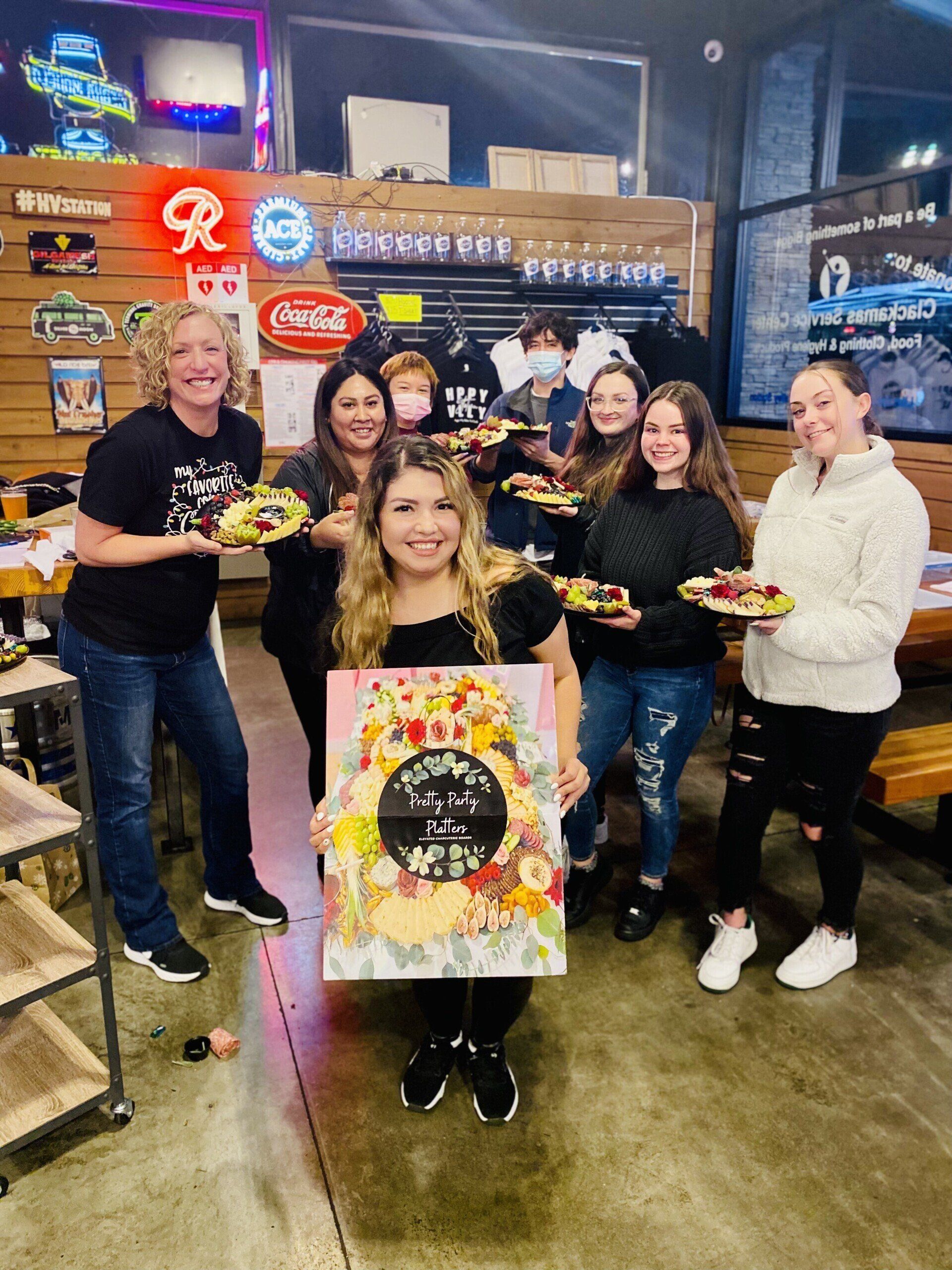 Group of people holding colorful plates and a painted sign in a restaurant.