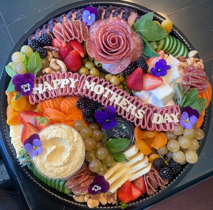 Charcuterie board with salami rose, fruit, cheeses, nuts, hummus, and