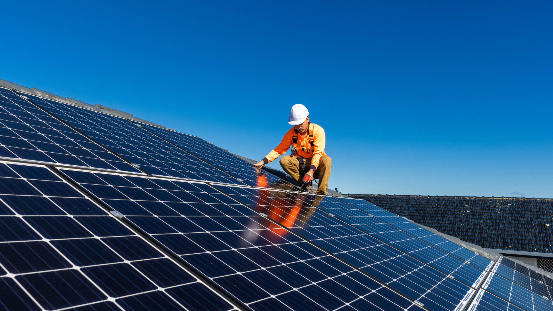 A man is installing solar panels on the roof of a building.