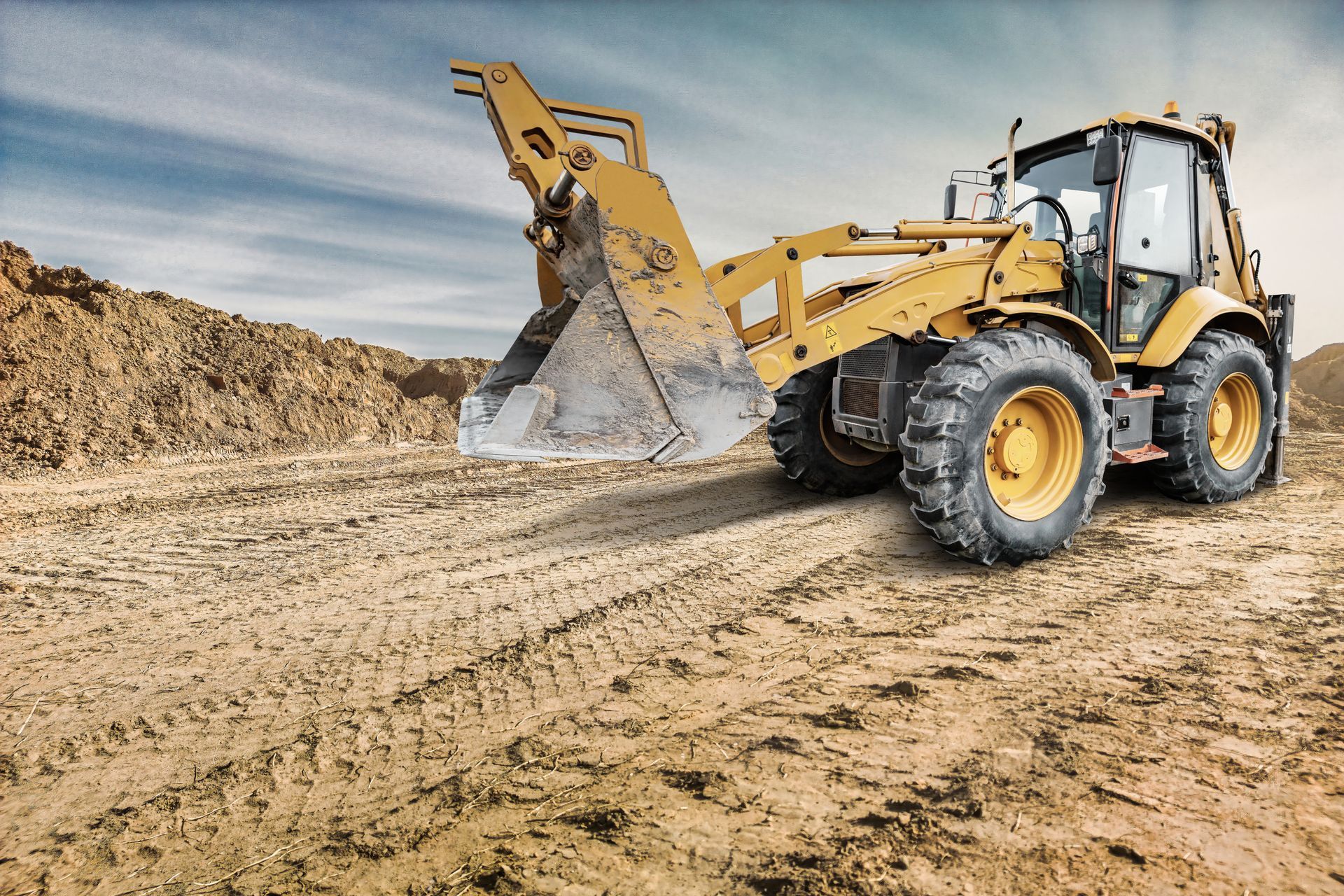 Yellow front loader moving dirt on a sandy construction site Yellow front loader moving dirt on a sandy construction site