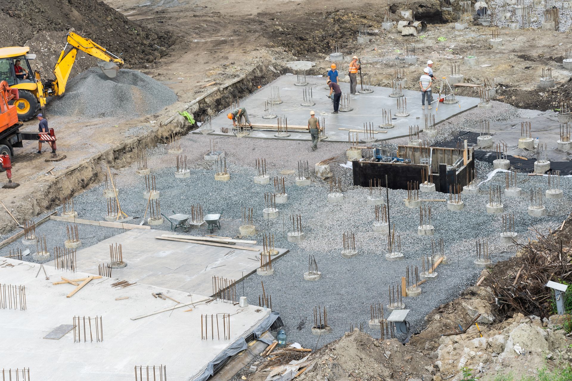 A construction site featuring a bulldozer and a crew of builders engaged in foundation piling