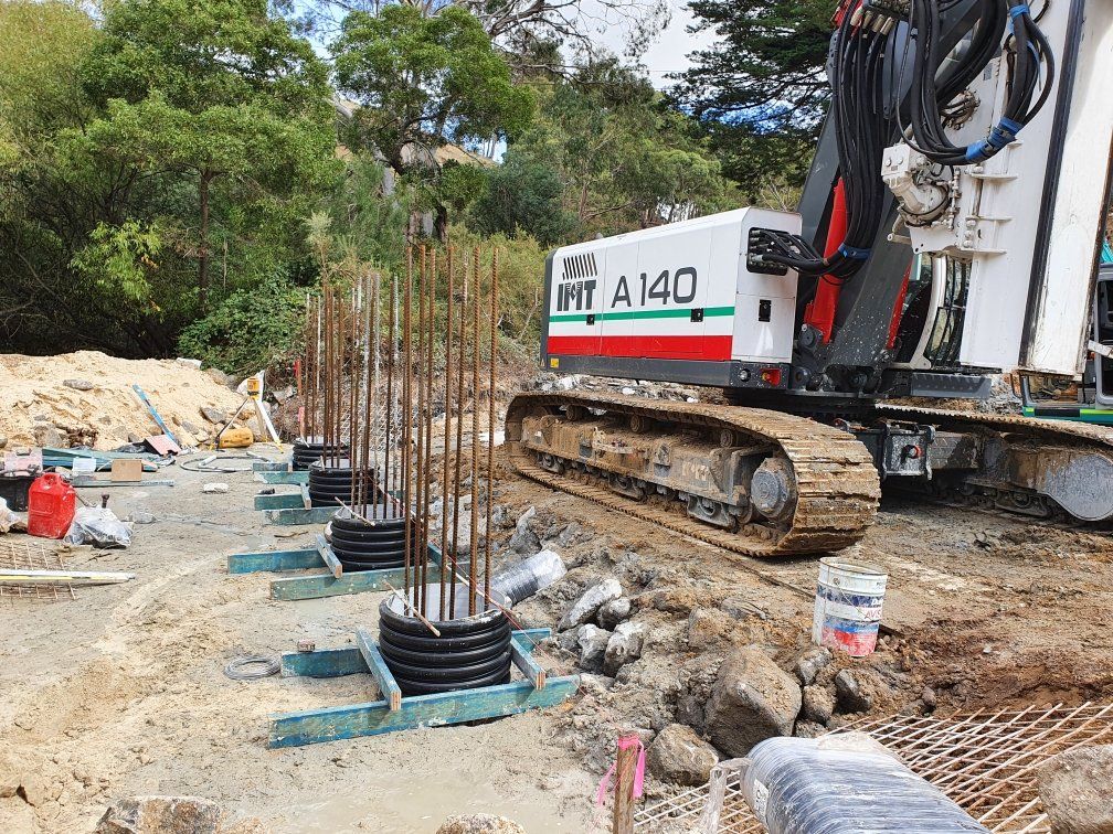 Construction excavator beside rebar and concrete forms on a dirt worksite