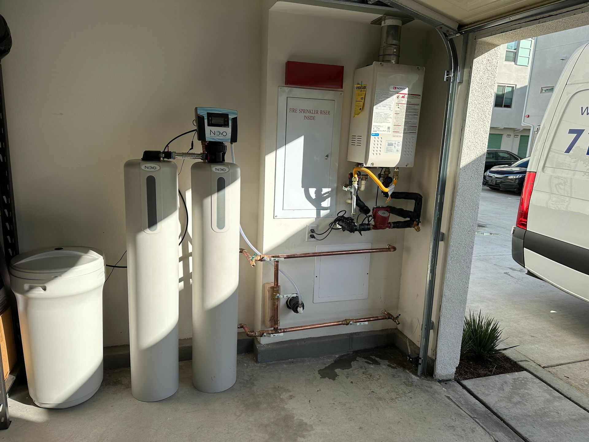 Garage with water softener, tankless water heater, and electrical panel. A white van is visible.