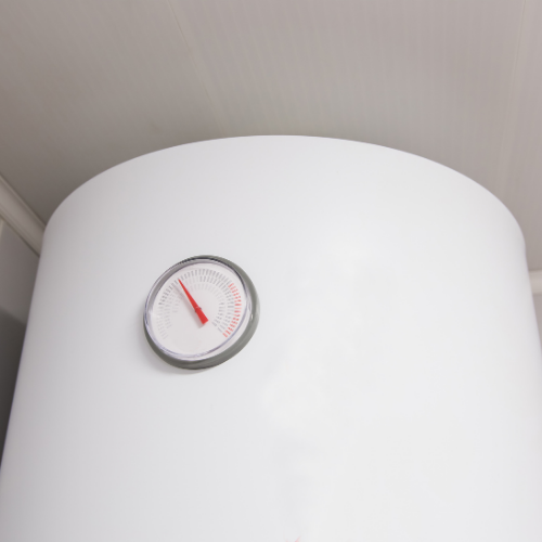 A white cylindrical water heater with a circular analog temperature gauge pointing towards the middle range.