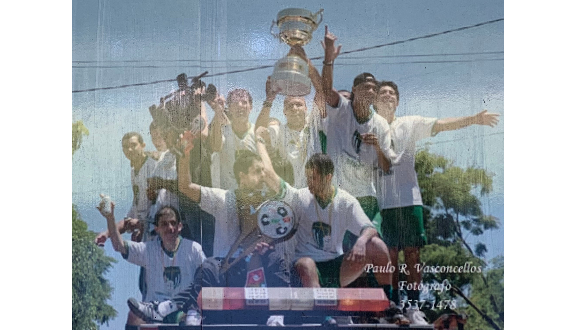Celebrando conquistas Um grupo de pessoas está em cima de um carro de polícia segurando um troféu.
