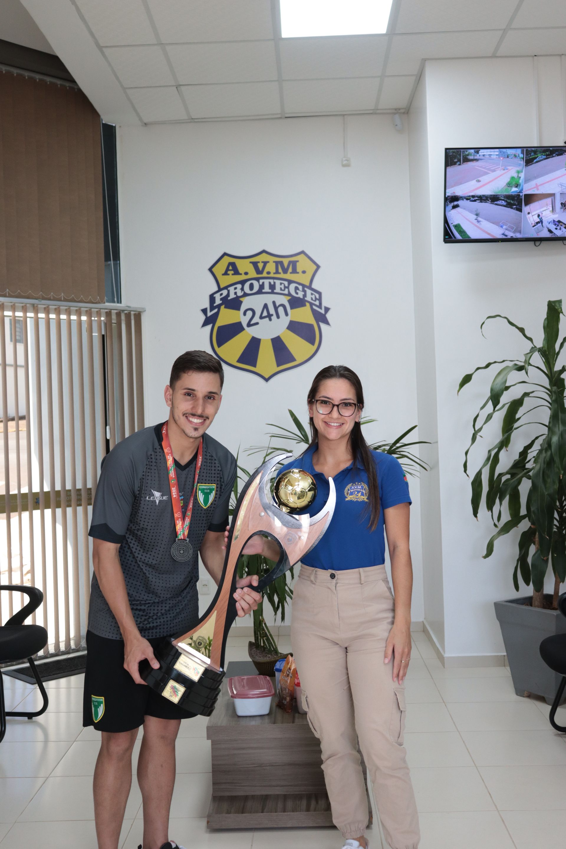 Um homem e uma mulher estão segurando um troféu em uma sala.
