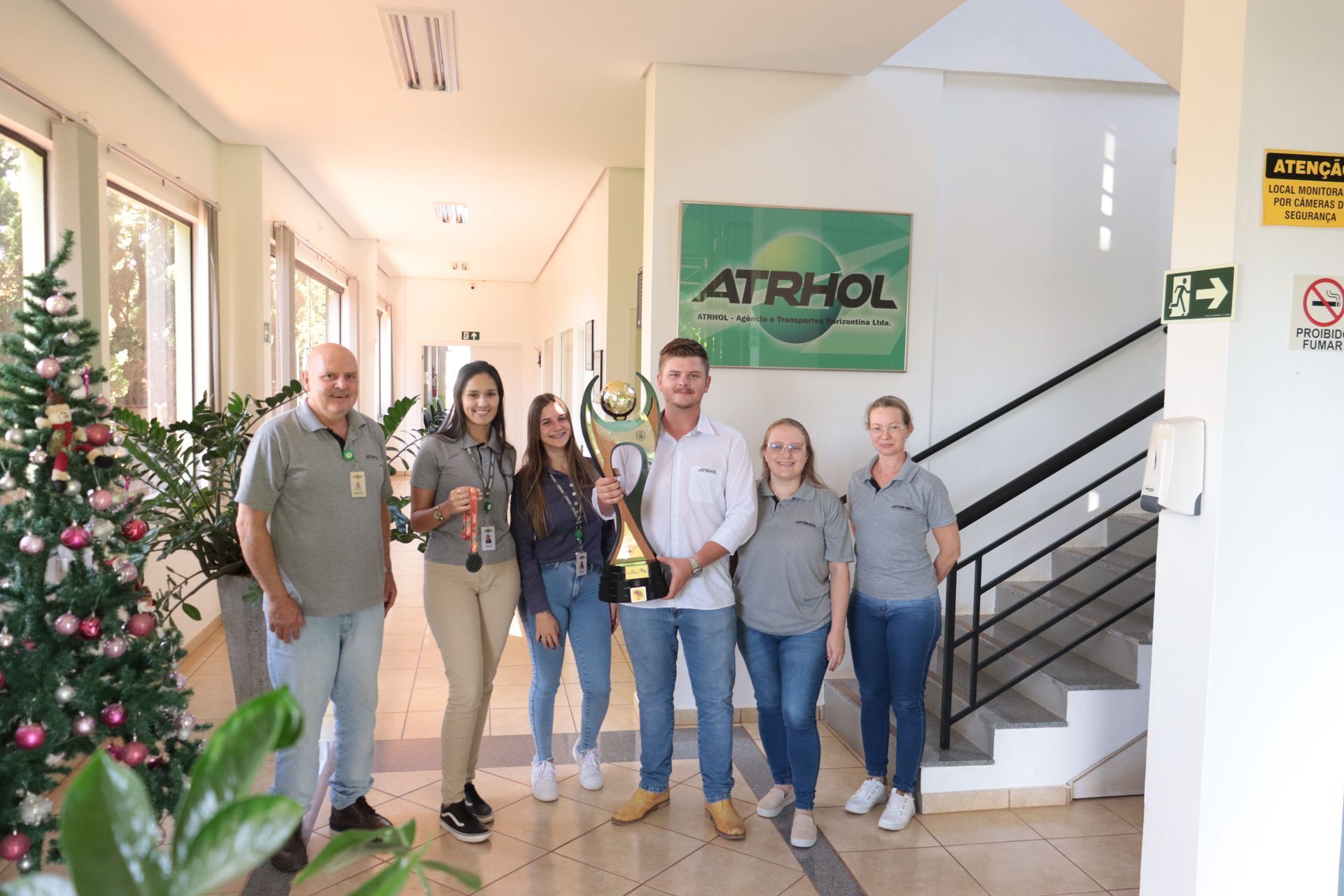 Um grupo de pessoas está em um corredor segurando um troféu.
