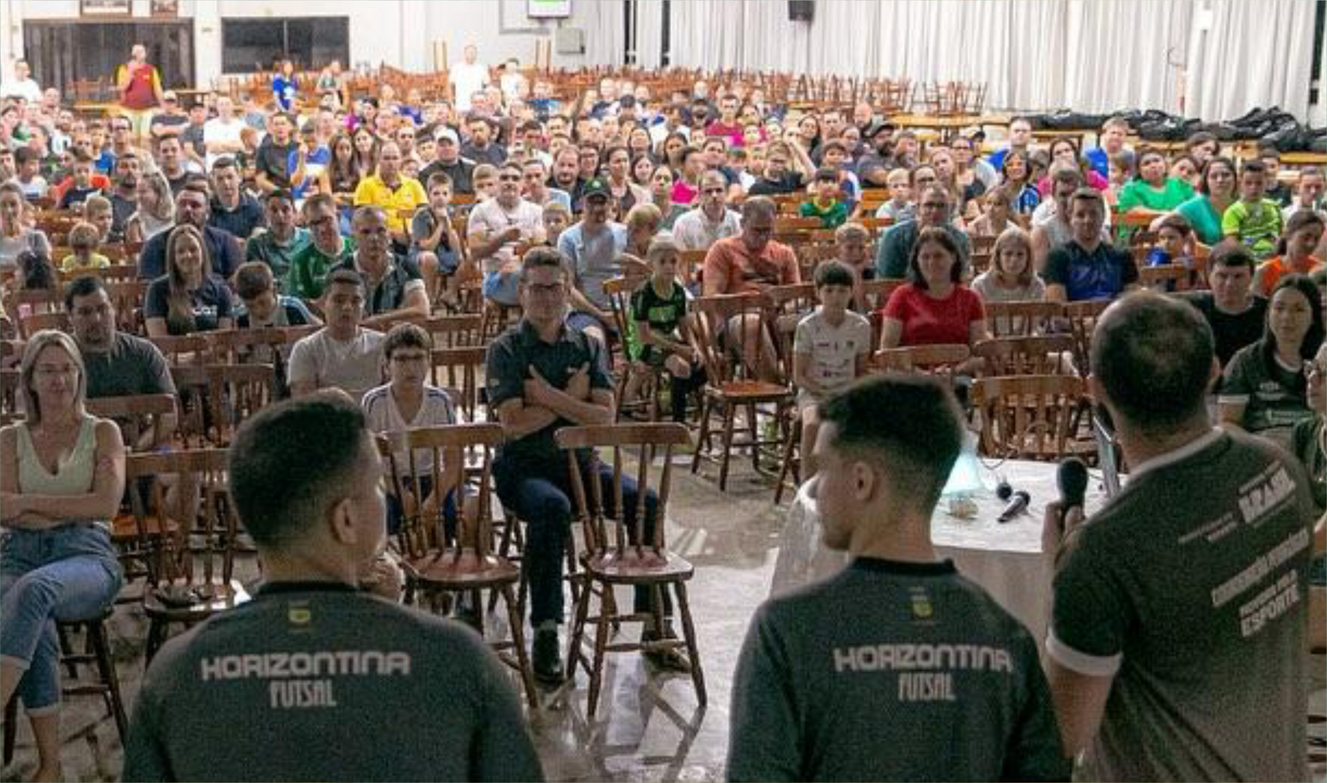 Um grupo de pessoas está em pé na frente de uma grande multidão palestrando.