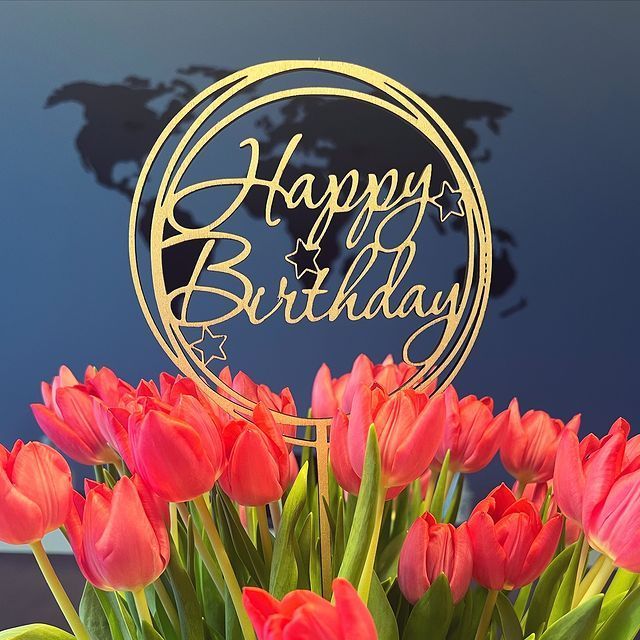 Ein Strauß roter Tulpen mit einem Happy Birthday-Schild im Hintergrund