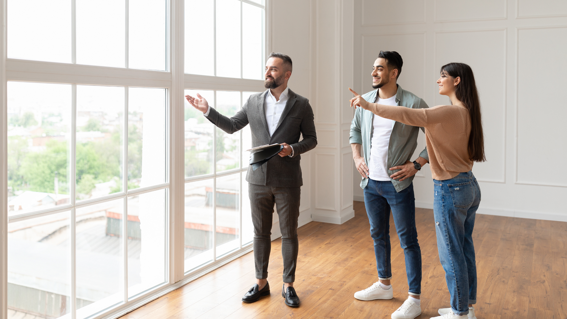 a man is showing a woman and a man a room with a lot of windows .