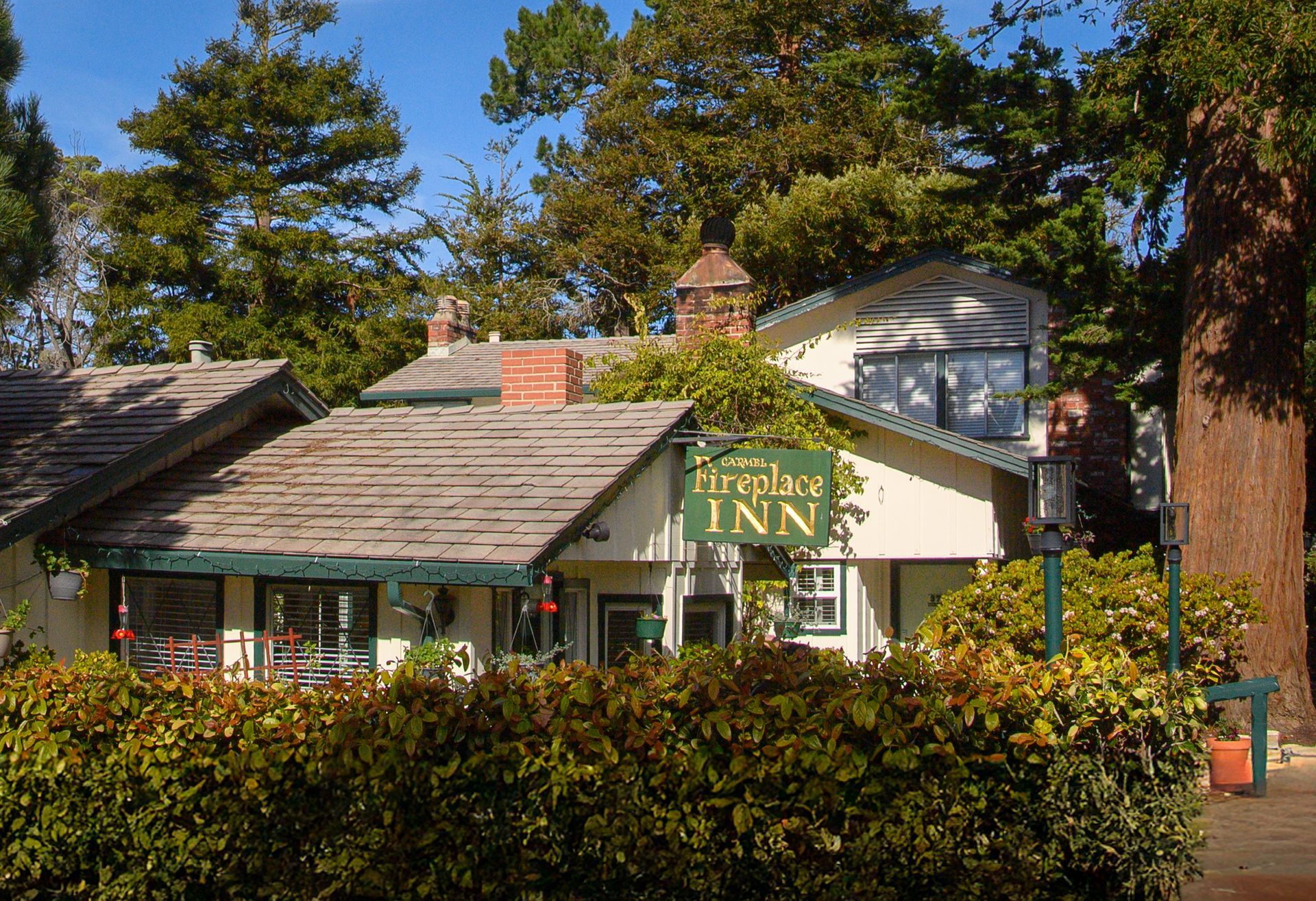 A cottage inn is surrounded by trees and bushes