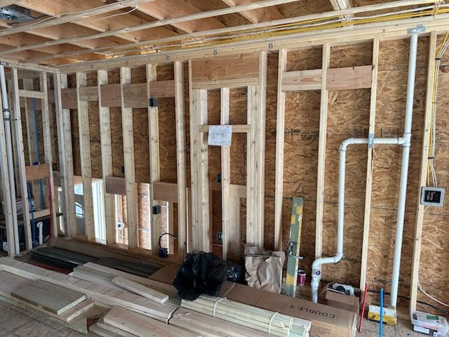 A room under construction with wooden beams and pipes.