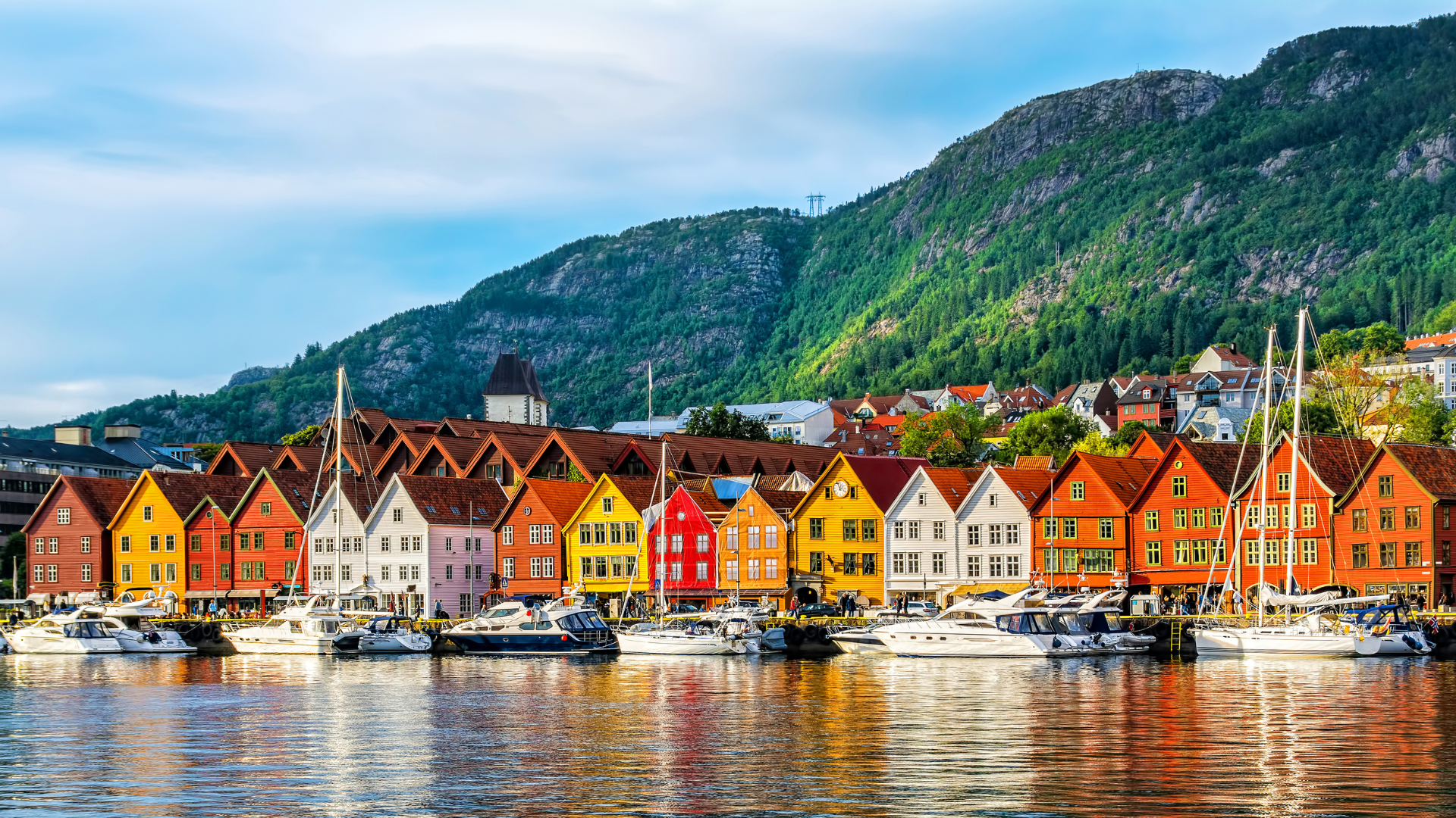 Kleurrijke, historische houten gebouwen sieren de waterkant van Bryggen in Bergen, Noorwegen, met boten die in de haven liggen aangemeerd.