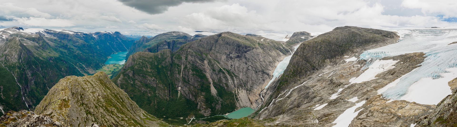 Een panoramisch uitzicht op de Jostedalsbreen-gletsjer in Noorwegen, met ruige bergen, ijsvelden en turquoise meren.