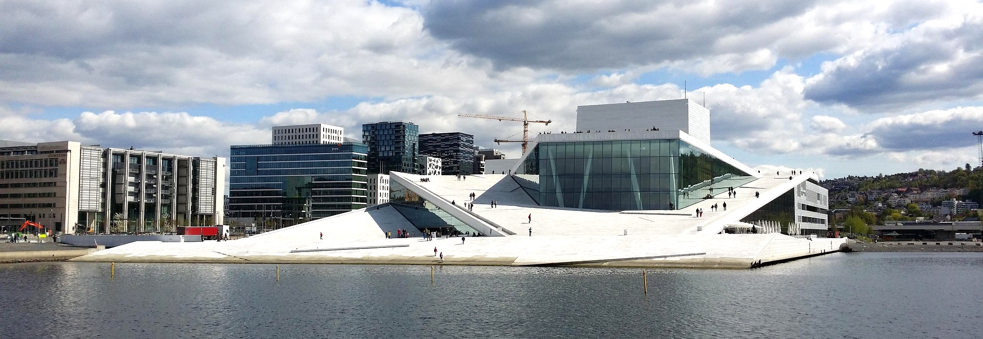 Een groot gebouw aan het water waar mensen op het dak lopen 