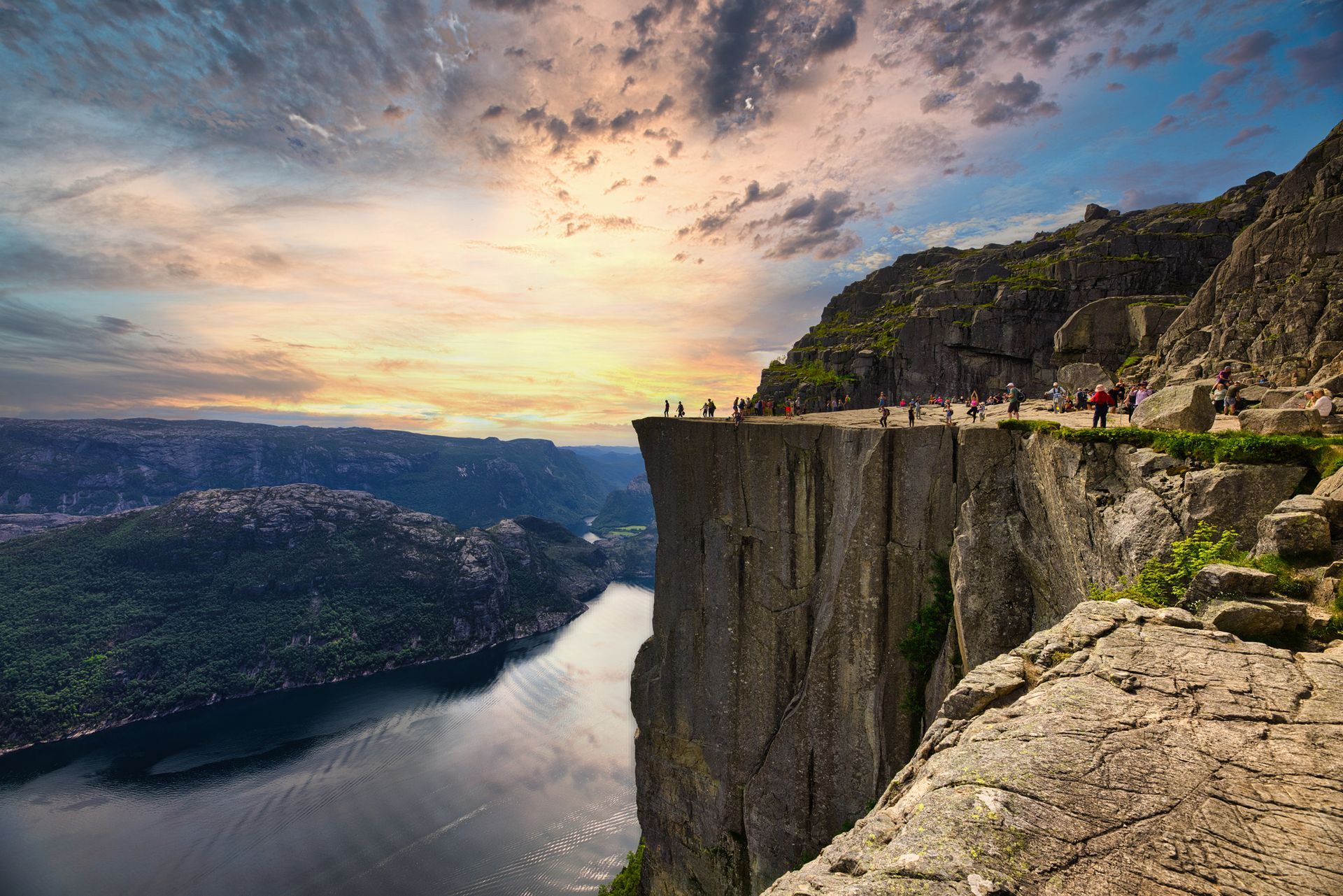 Adembenemend uitzicht op Preikestolen, de beroemde klif in Noorwegen, met groene bergen en een helderblauwe lucht.