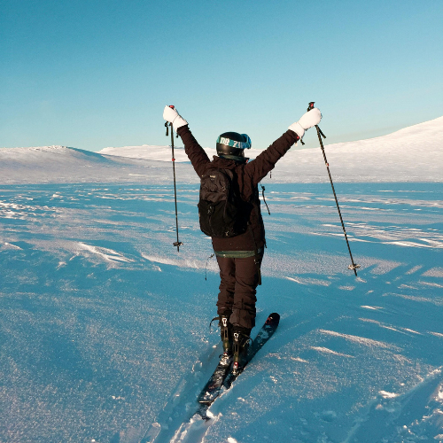 Een persoon op ski's met zijn armen in de lucht