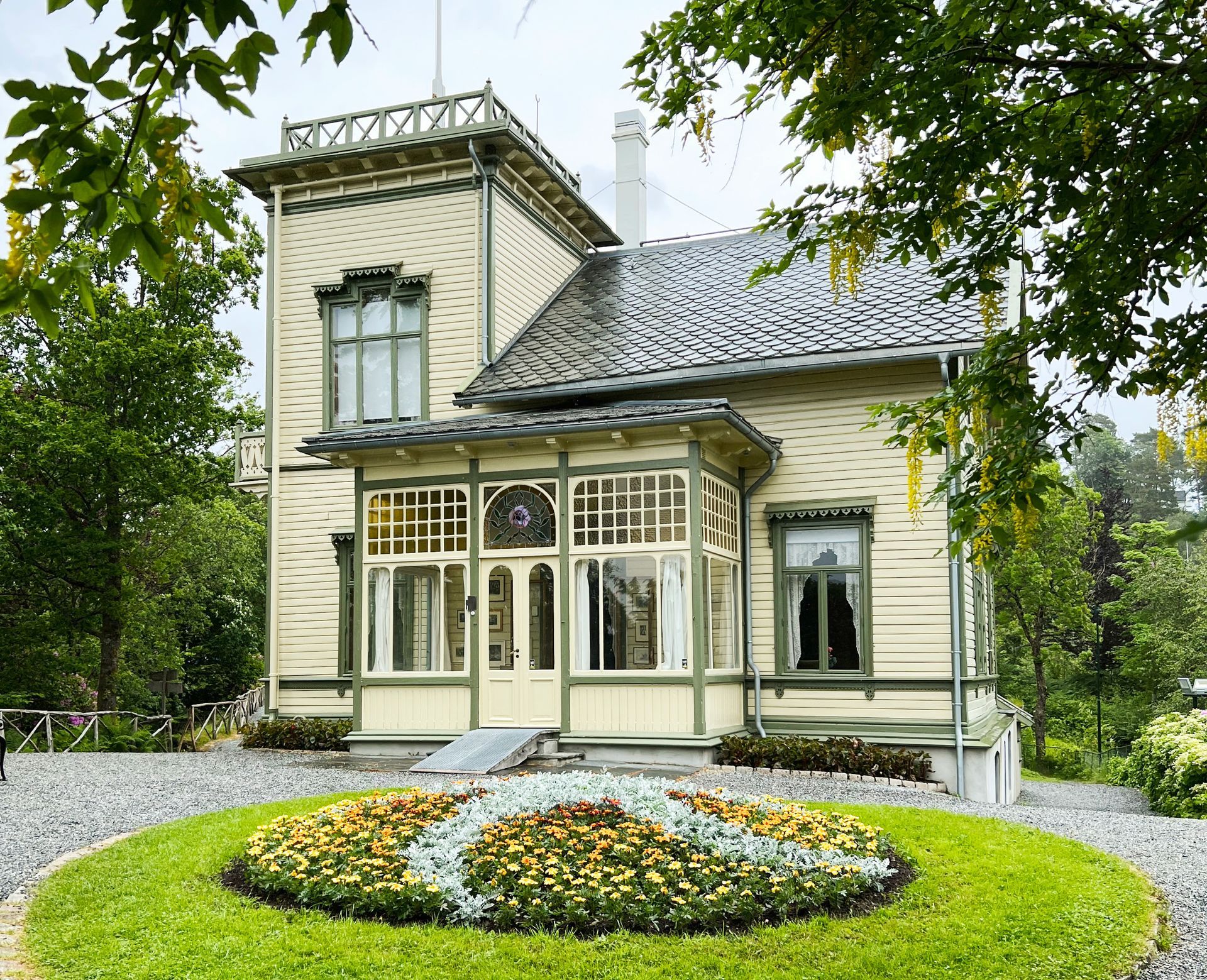 Een groot wit huis met een cirkelvormig bloemenperk ervoor.