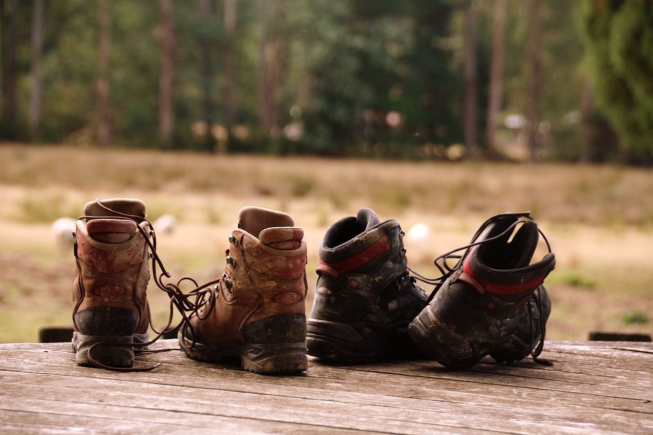 Op een houten tafel staan drie paar wandelschoenen.