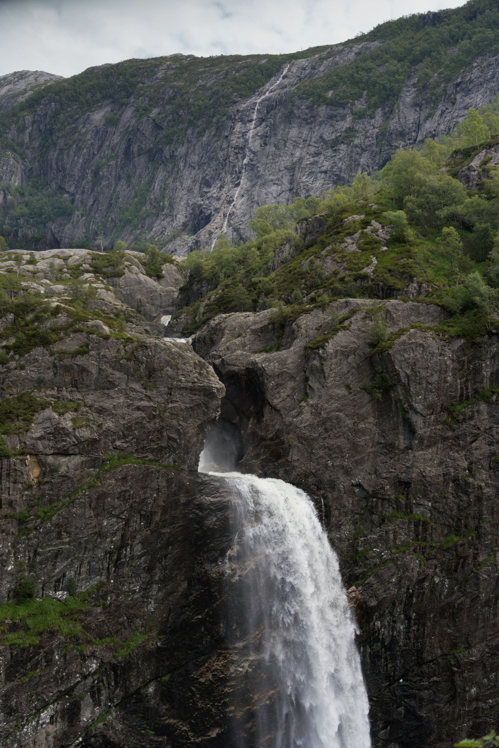 Een waterval in het midden van een berg, omgeven door bomen.