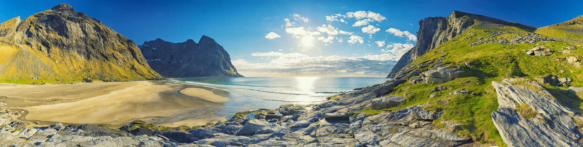 Een panoramisch uitzicht op een strand omgeven door bergen en een watermassa.