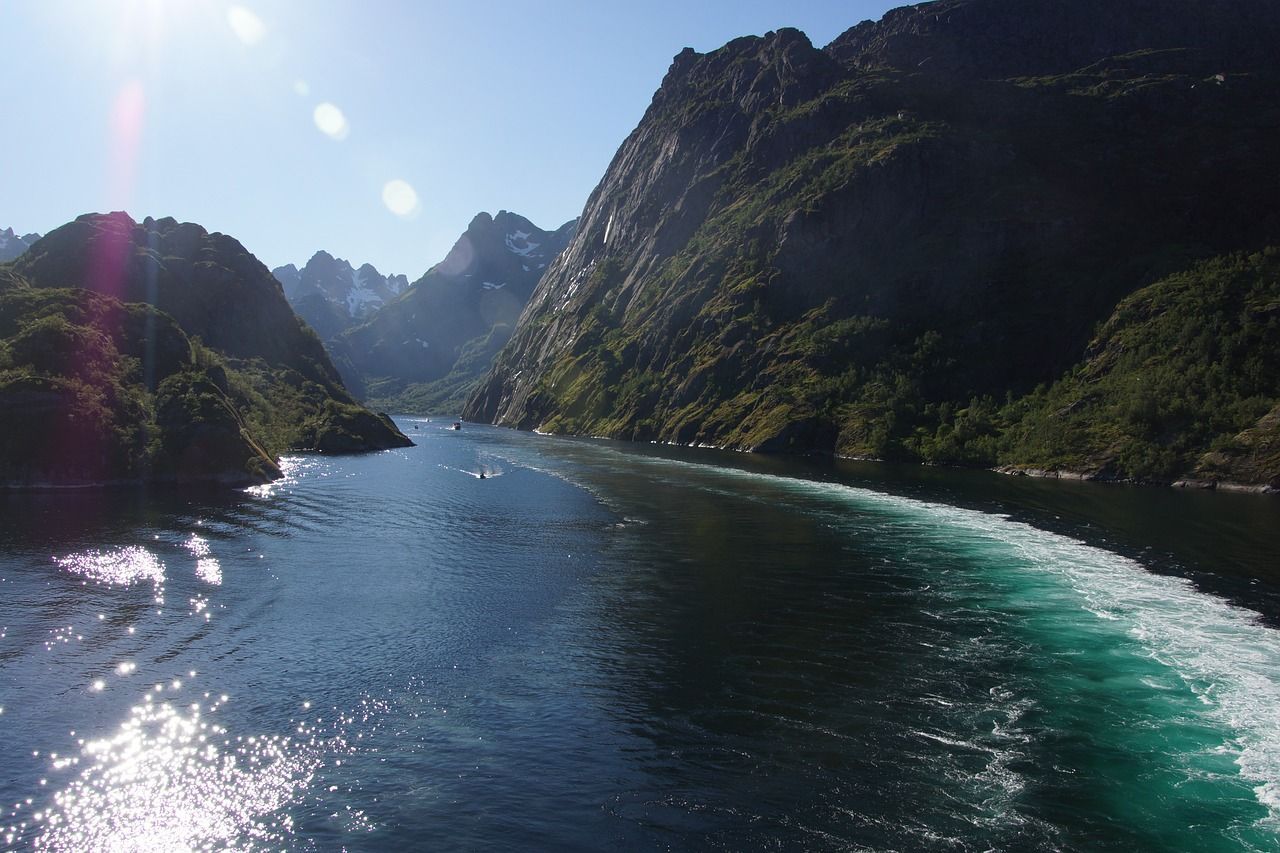 Een boot vaart over een fjord met bergen op de achtergrond.