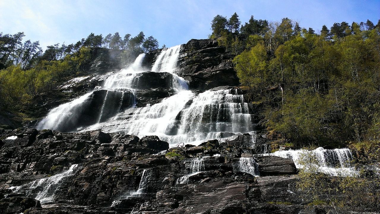 Een waterval is omgeven door bomen en rotsen