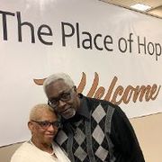 Older couple smiling in front of a banner that reads 