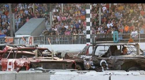 A group of wrecked cars are racing on a race track.
