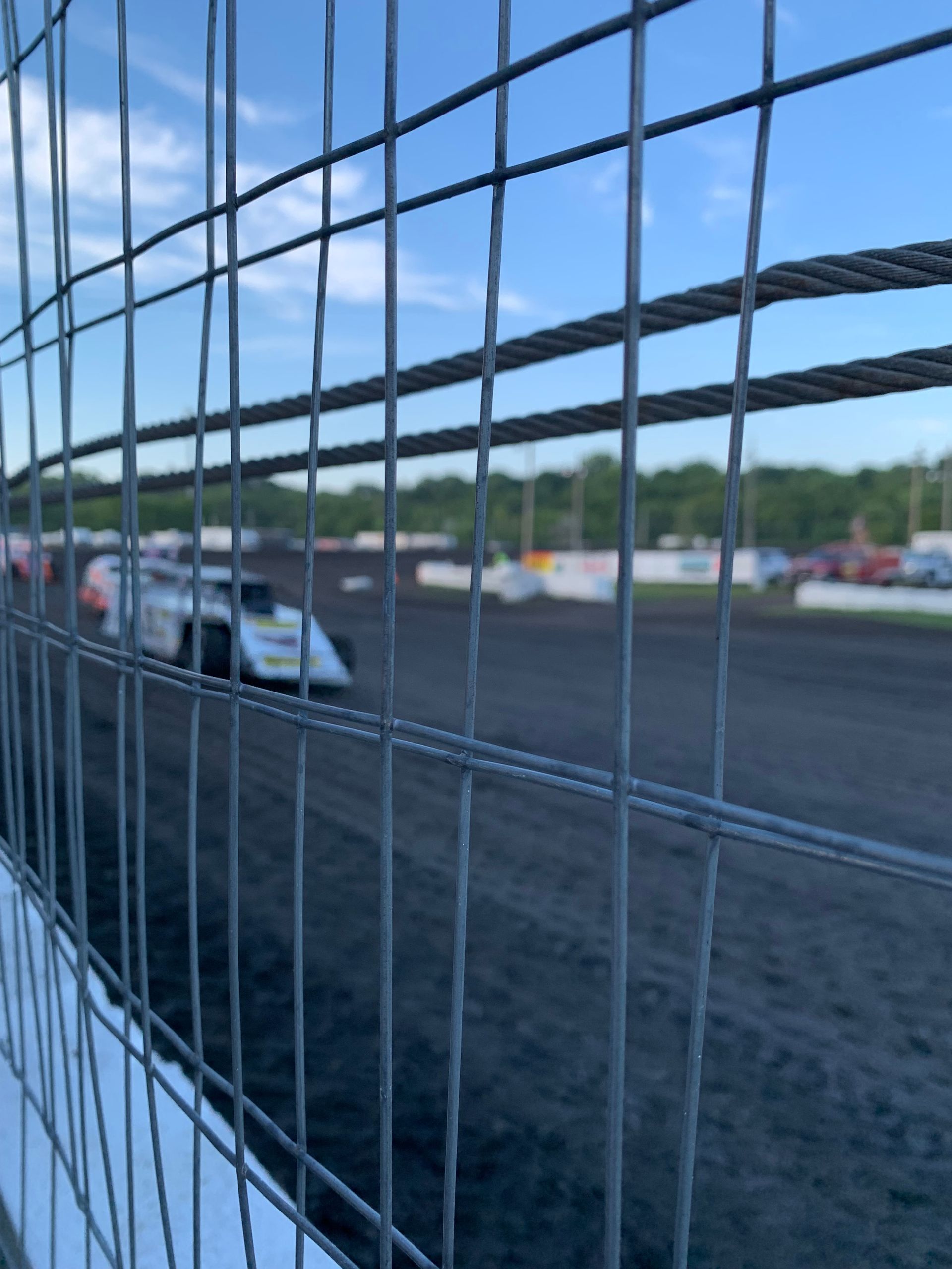 A race car is driving down a track behind a fence