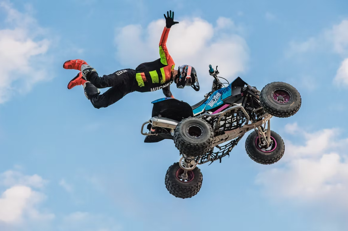 Close-up of a dirt bike tire kicking up a large cloud of brown earth while turning on a dirt track.