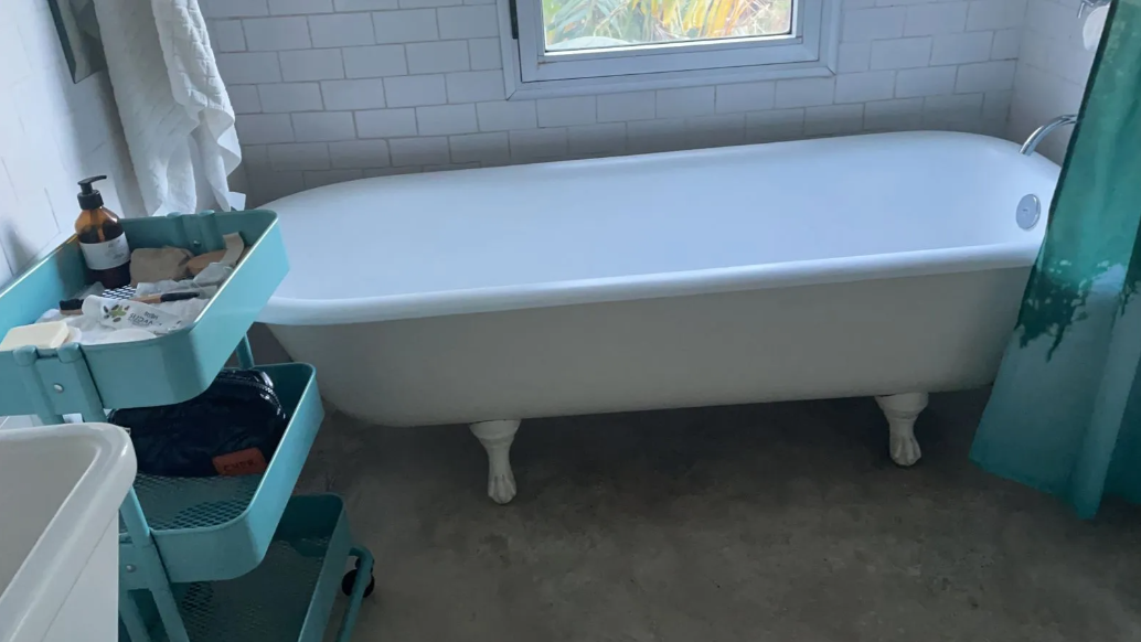 Bañera blanca con patas en un baño luminoso.