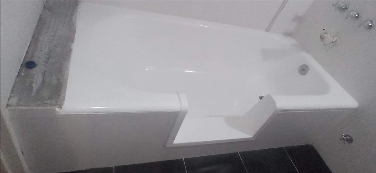 Lavabo blanco montado en la pared con secador de manos incorporado en un baño alicatado.