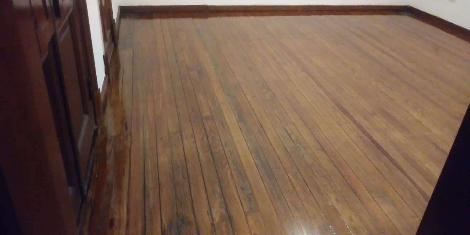 Suelo de madera en una habitación vacía, vista desde una puerta.