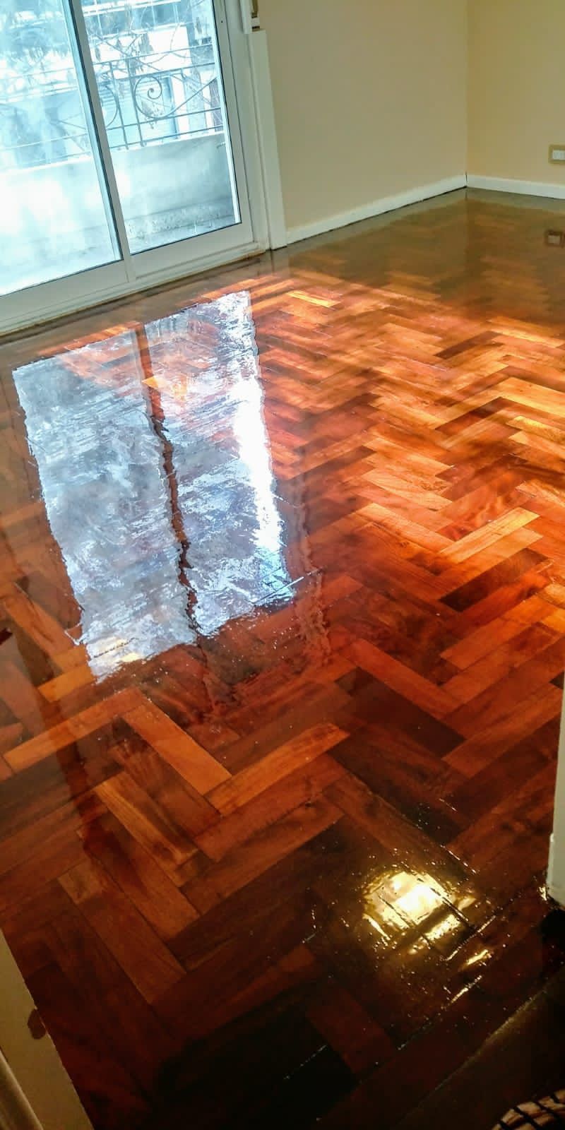 Un brillante suelo de madera noble con el reflejo luminoso de una ventana en una habitación vacía.