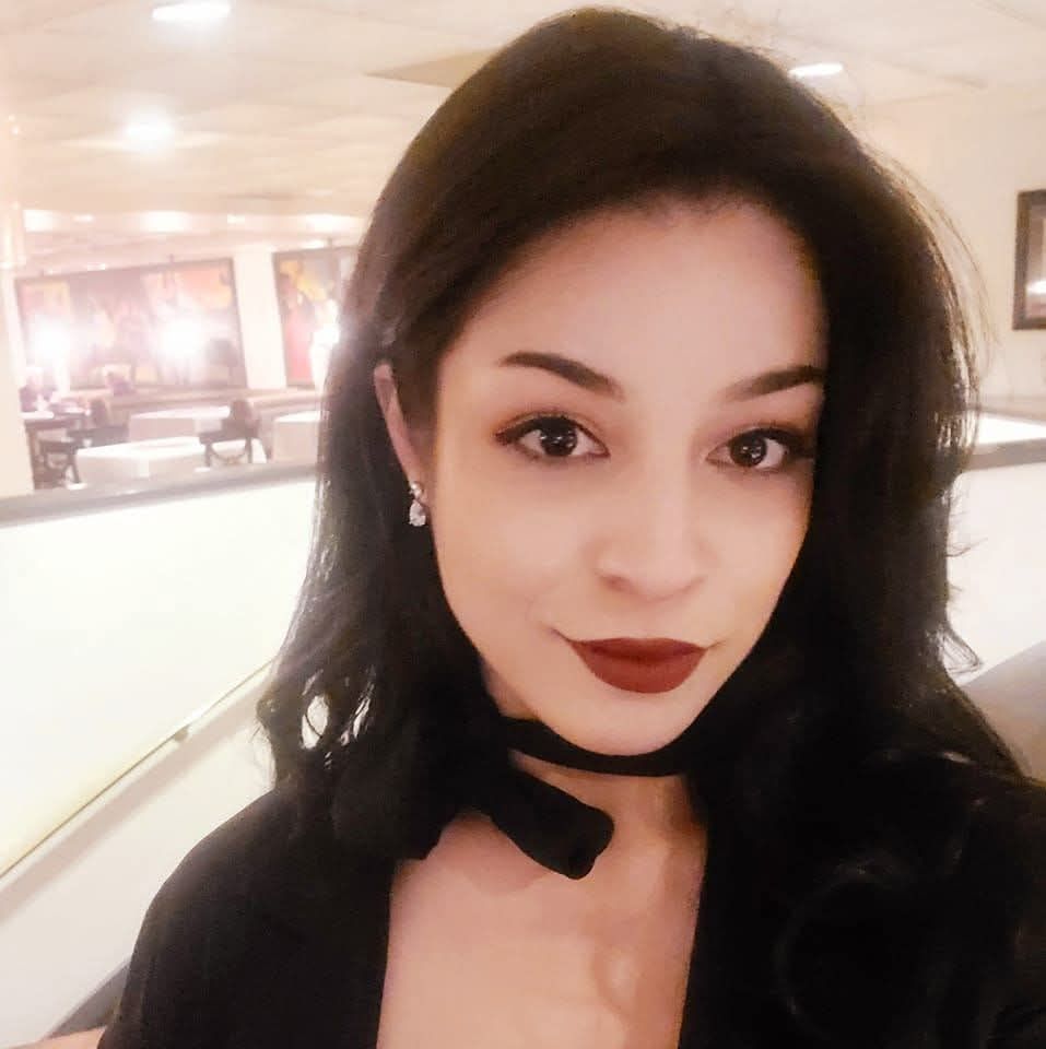 Portrait of a woman with dark hair and red lipstick in a softly lit indoor lobby