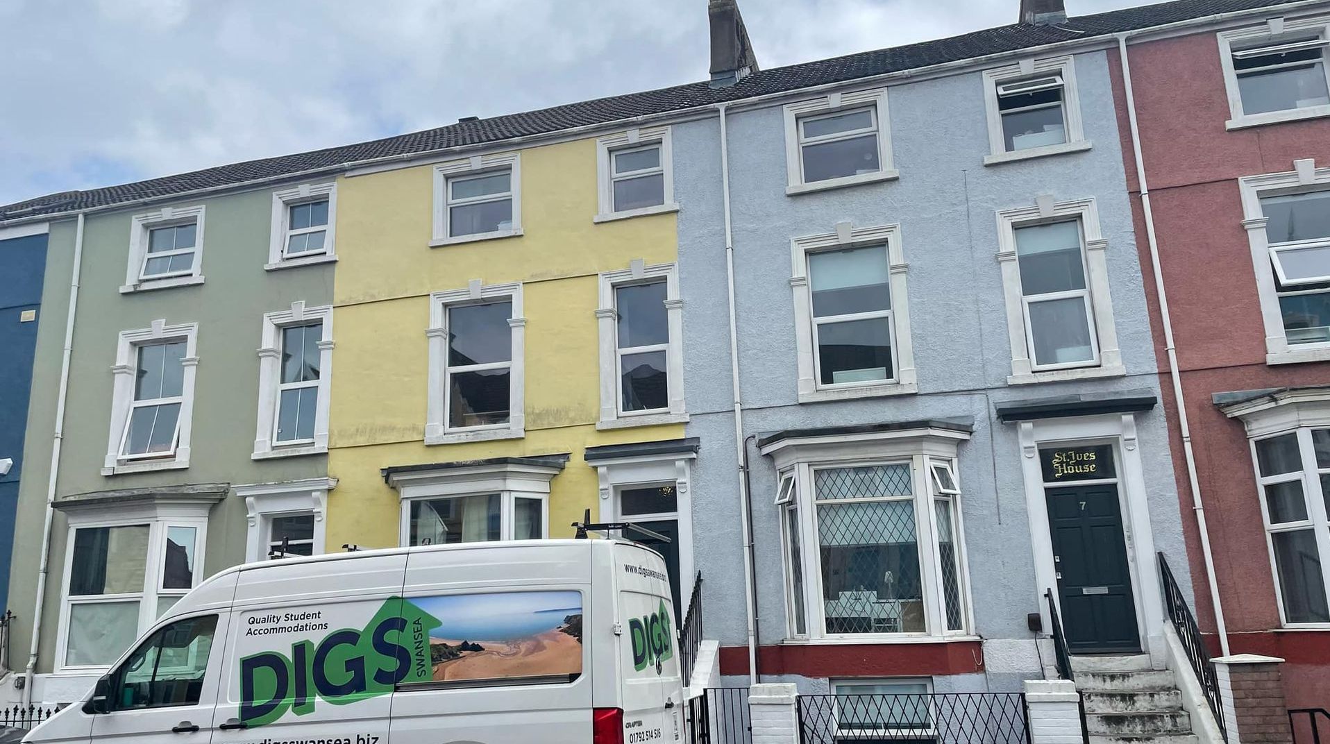 Row of colorful houses; van parked in front. Green, yellow, blue, and red painted buildings.