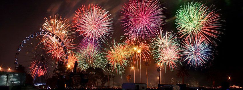 Fireworks exploding in the night sky above a city skyline with a ferris wheel.