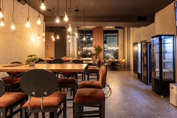 Cozy modern café with wooden tables, pendant lights, and glass-door refrigerators along the wall