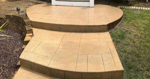 Stone steps leading to a structure on a lawn. Beige bricks. Curving design.