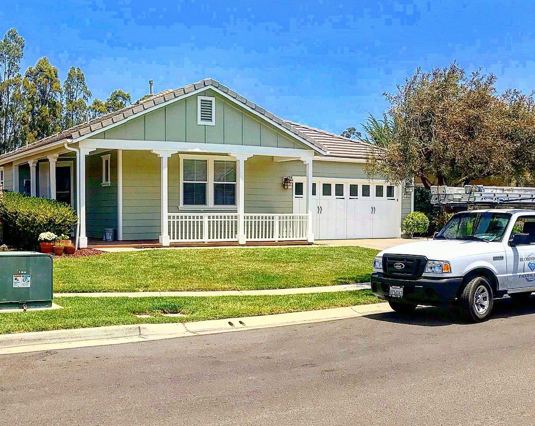 Light green house with white porch and garage, parked white truck.