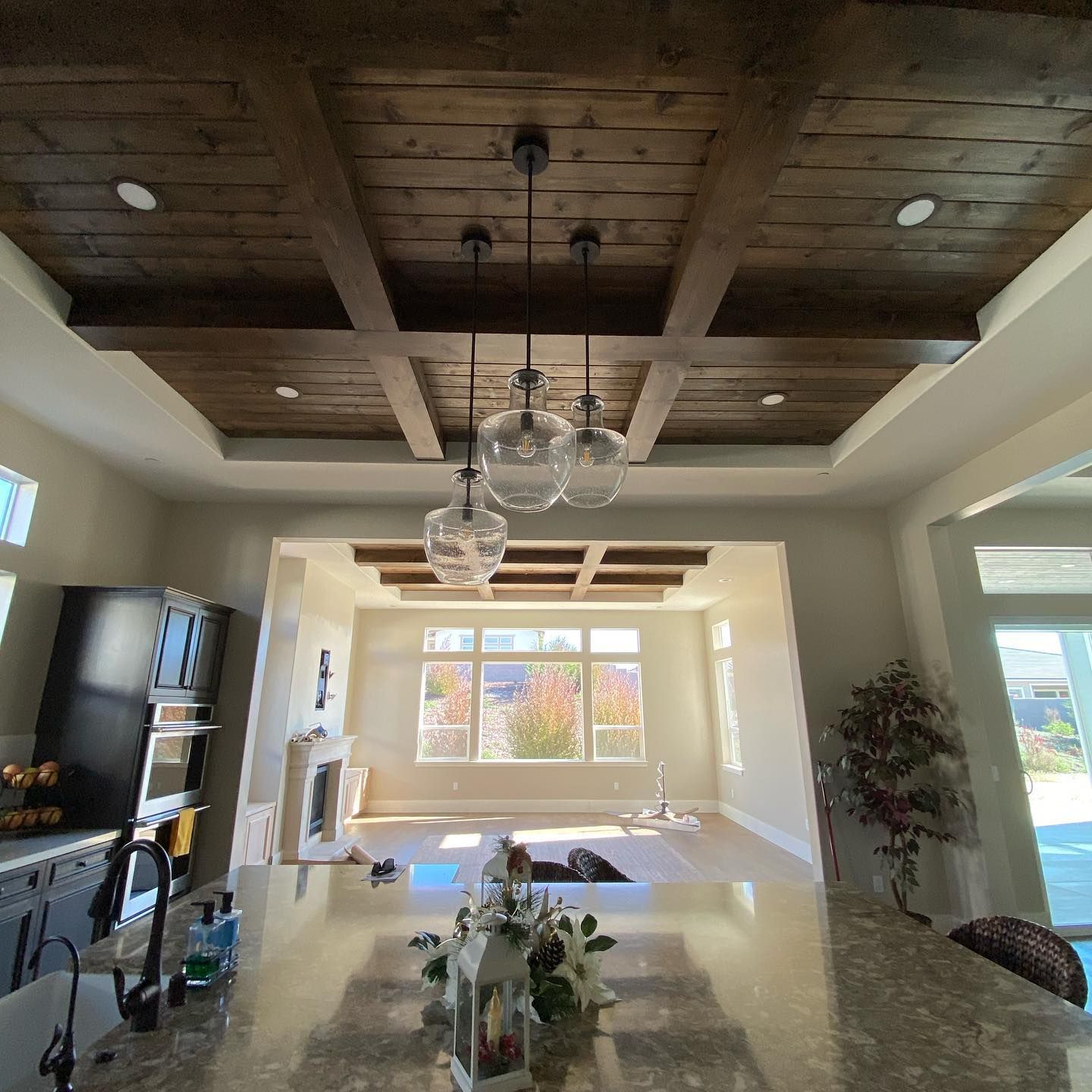 Interior view of a kitchen and living space with a wooden beam ceiling and pendant lights.